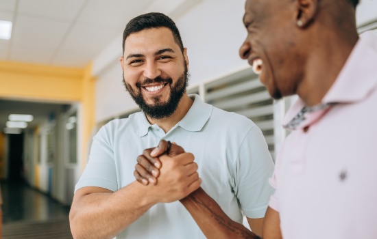 Two people shaking hands to symbolize connection and encouragement in peer support services